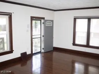 Empty room featuring ornamental molding, wood finished floors, and a textured ceiling
