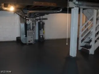 Unfinished below grade area featuring gas water heater, concrete block wall, and heating unit