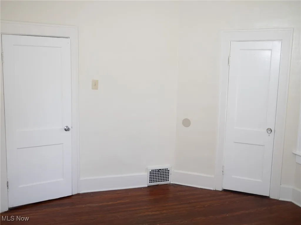 Spare room with dark wood-style floors and baseboards