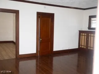 Spare room featuring wood finished floors, crown molding, and a textured ceiling
