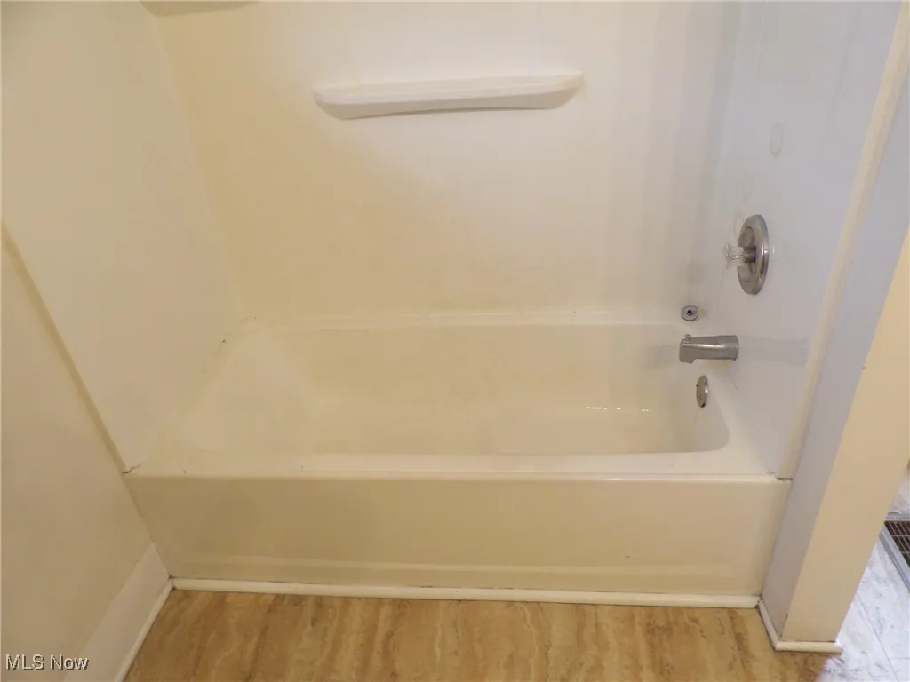 Full bath featuring baseboards, bathing tub / shower combination, and wood finished floors