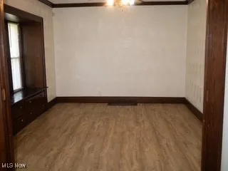 Empty room with ornamental molding, ceiling fan, and wood finished floors