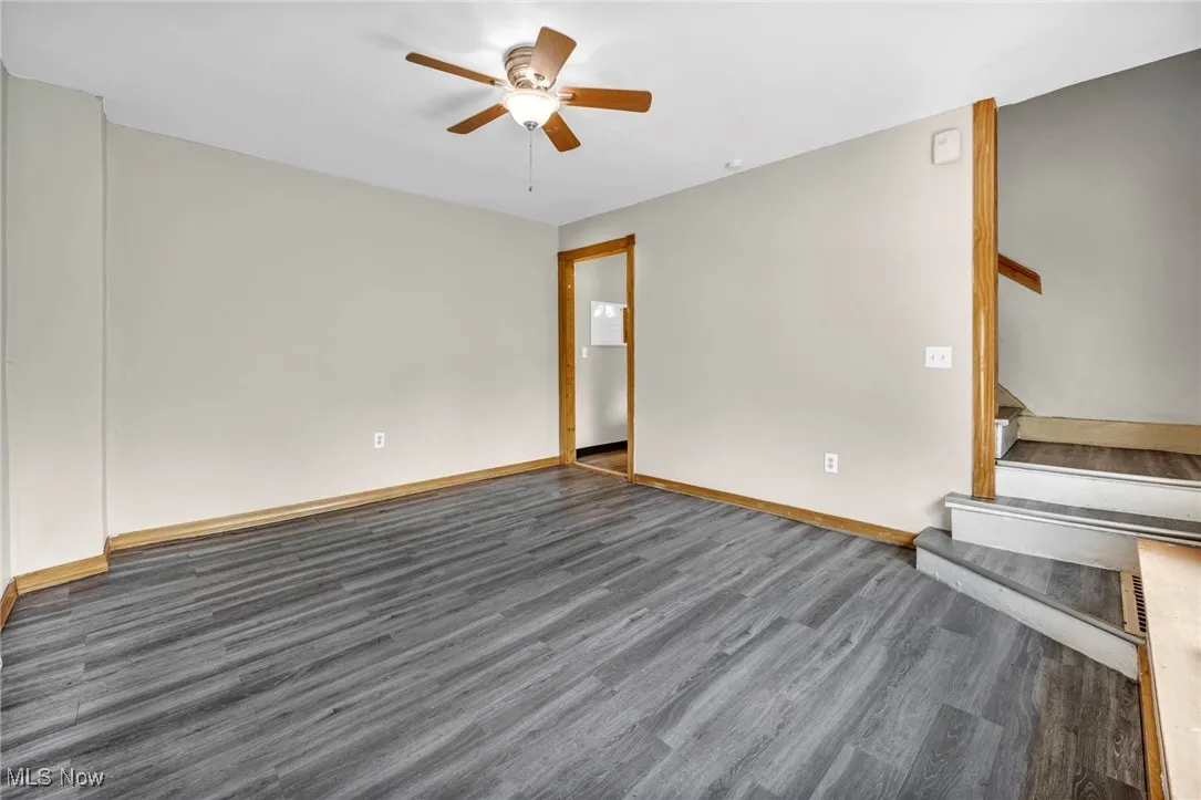 Spare room with wood finished floors, ceiling fan, stairway, and baseboards