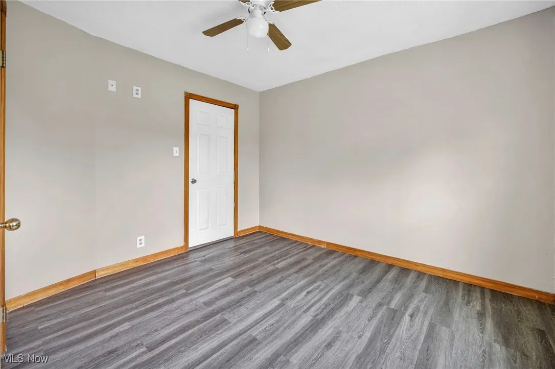 Empty room with wood finished floors, a ceiling fan, and baseboards