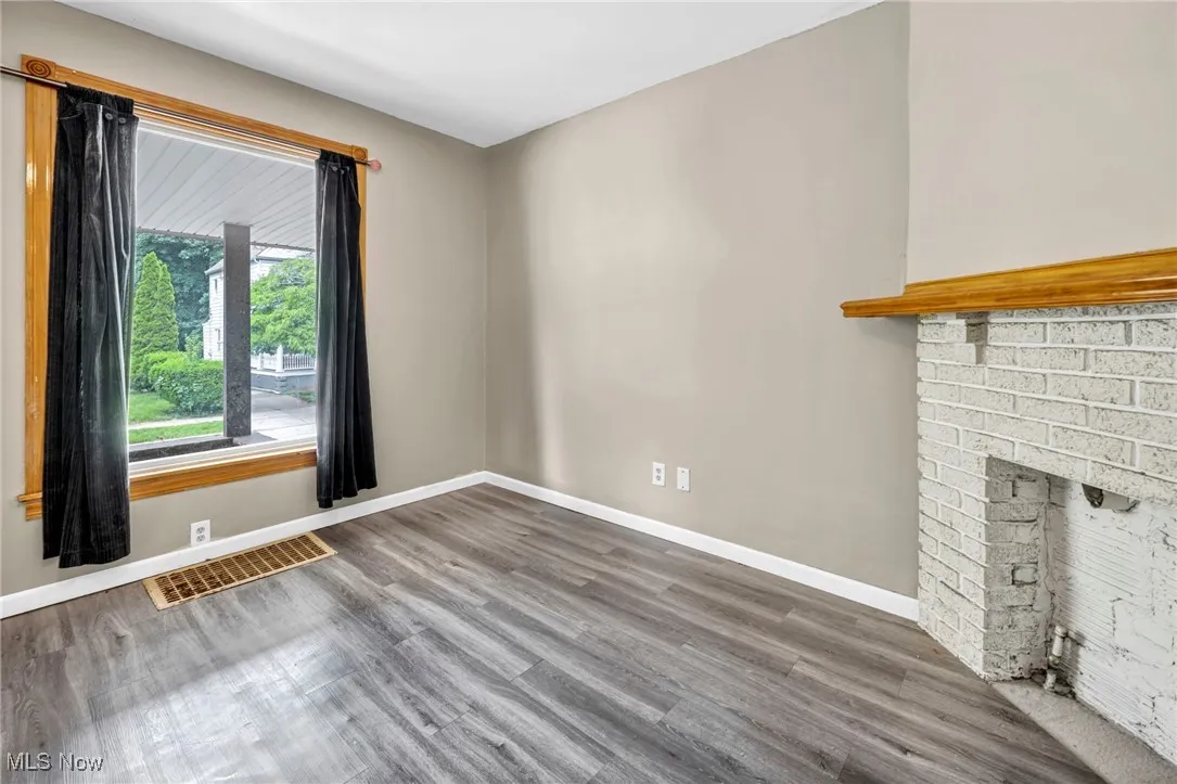 Unfurnished living room featuring wood finished floors, baseboards, and a fireplace