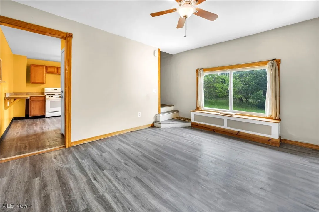 Unfurnished room with a ceiling fan, wood finished floors, and baseboards