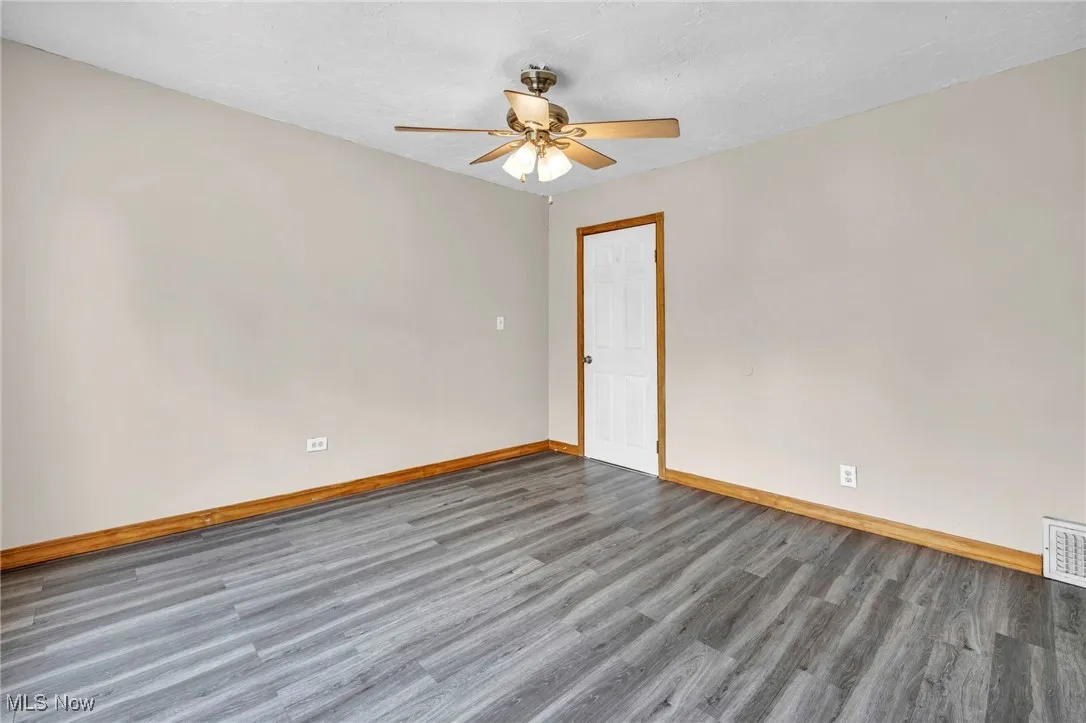 Unfurnished room featuring wood finished floors, baseboards, and ceiling fan