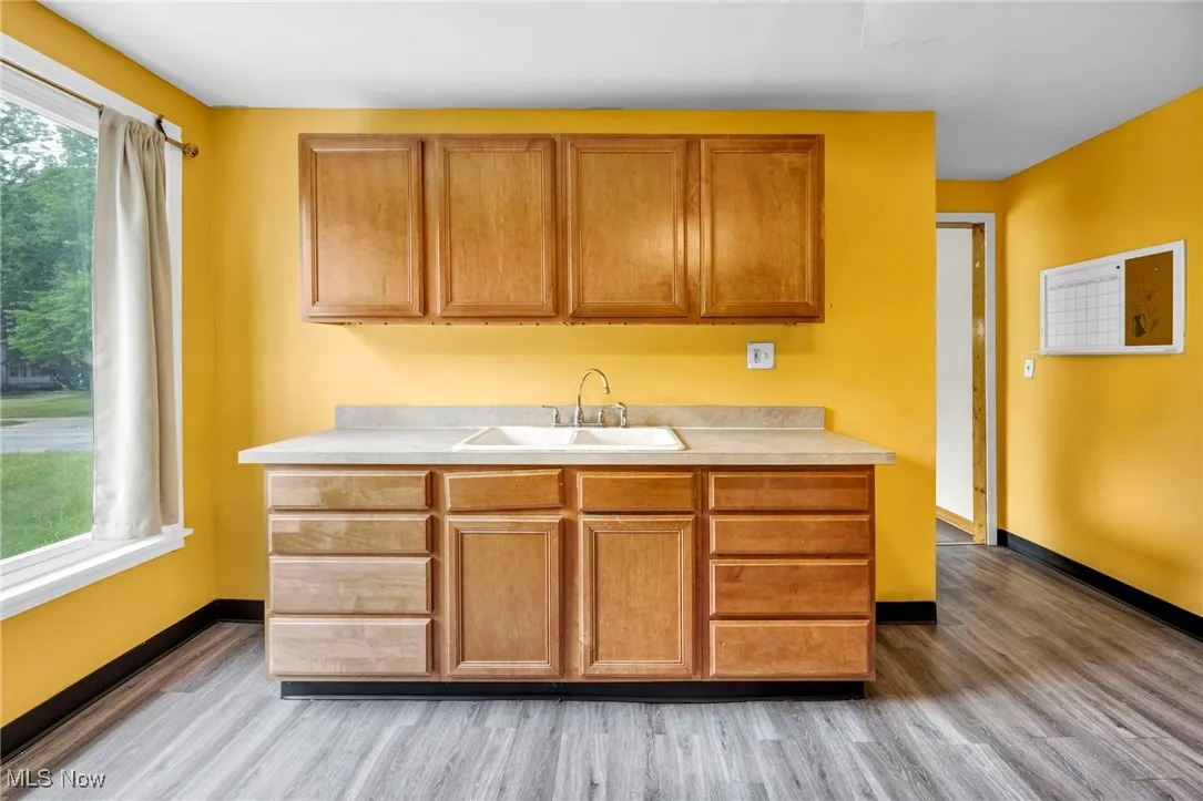 Kitchen featuring a sink, light wood finished floors, light countertops, and baseboards