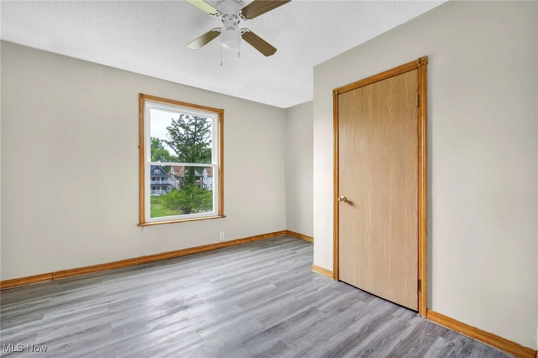 Unfurnished bedroom with wood finished floors, baseboards, a ceiling fan, and a textured ceiling
