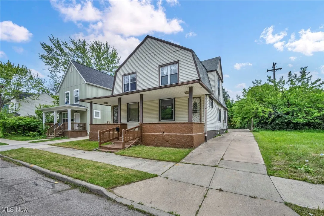 Dutch colonial with a gambrel roof, covered porch, and a front lawn