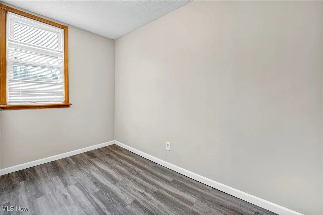Empty room with baseboards, wood finished floors, and a textured ceiling