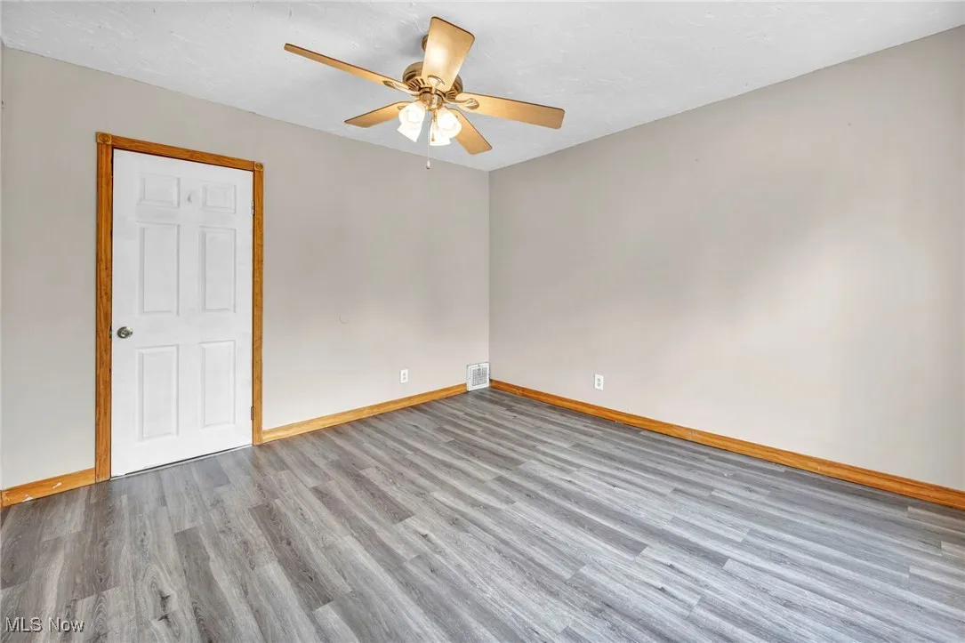 Unfurnished room with wood finished floors, baseboards, a ceiling fan, and a textured ceiling