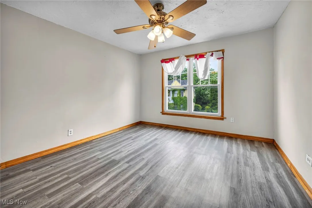 Spare room with wood finished floors, baseboards, and ceiling fan