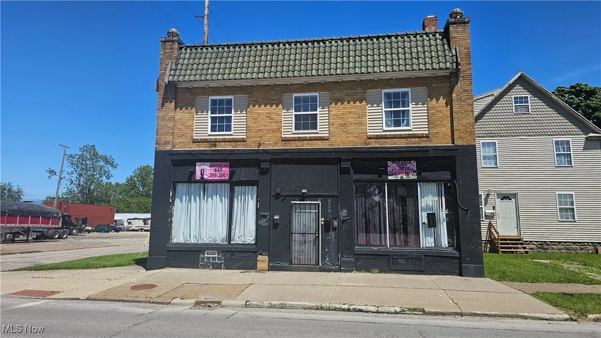 View of front of property featuring a chimney, a tile roof, brick siding, and entry steps