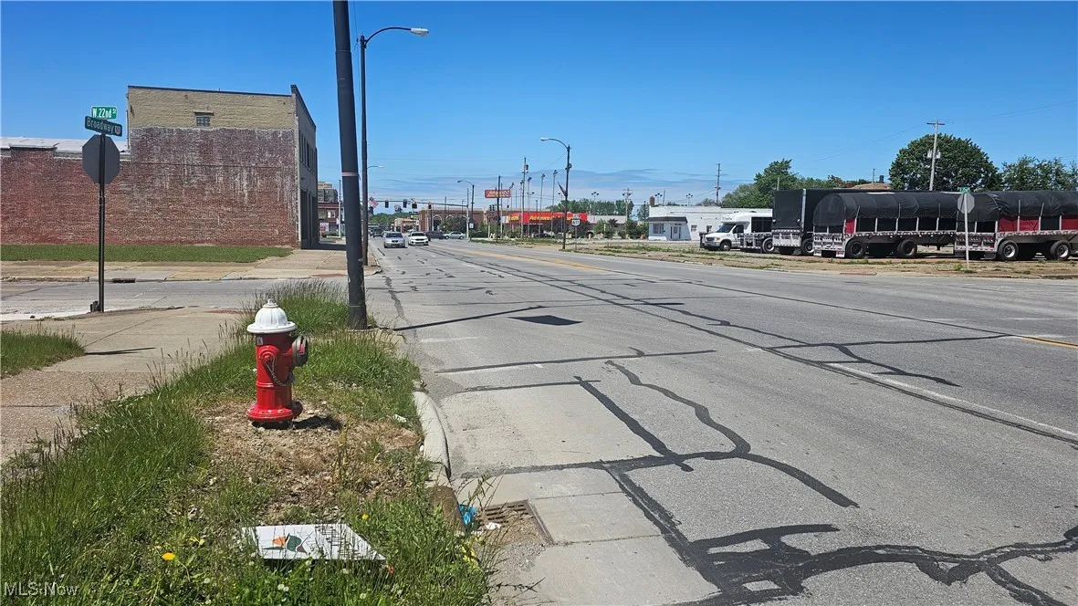 View of asphalt road featuring traffic signs, curbs, street lighting, and sidewalks