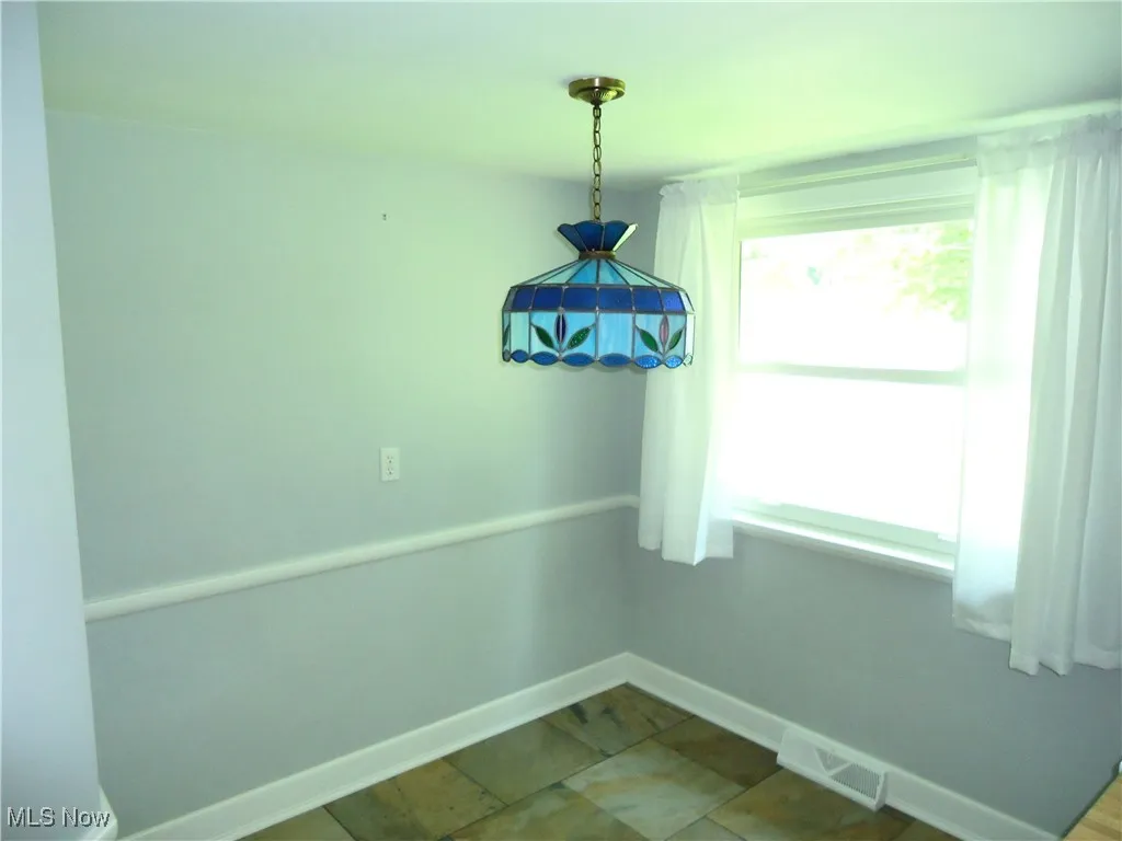 Unfurnished dining area featuring baseboards