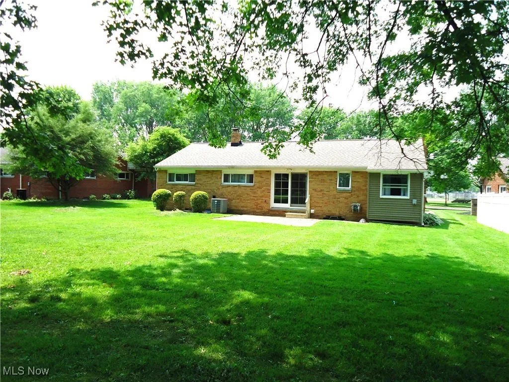 Back of house featuring cooling unit, a chimney, a patio area, and brick siding