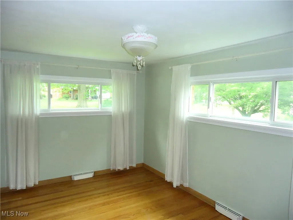 Spare room featuring baseboard heating, light wood-type flooring, and baseboards