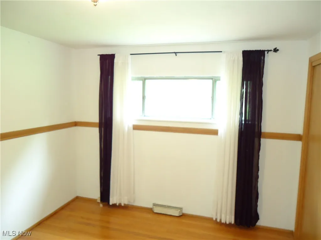 Empty room with a baseboard radiator and light wood finished floors