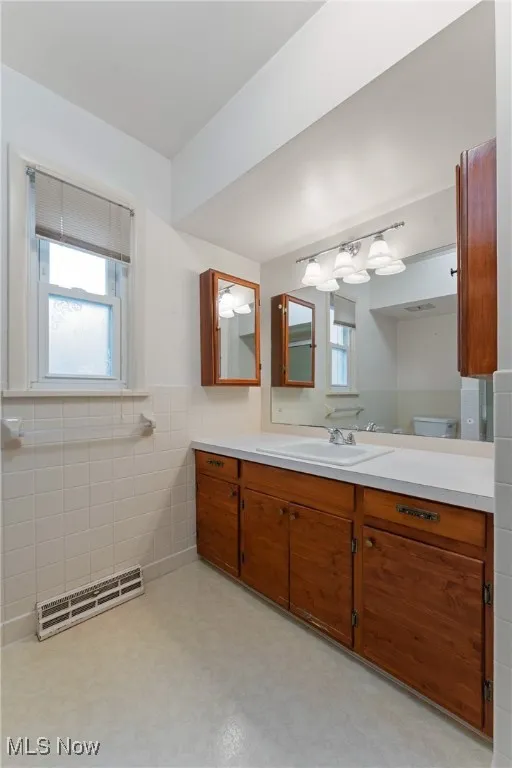Bathroom featuring tile walls, plenty of natural light, vanity, and a wainscoted wall