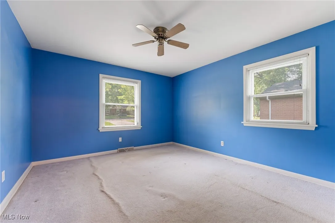 Carpeted empty room with baseboards and ceiling fan