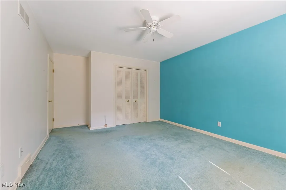Unfurnished bedroom with a closet, carpet, and a ceiling fan