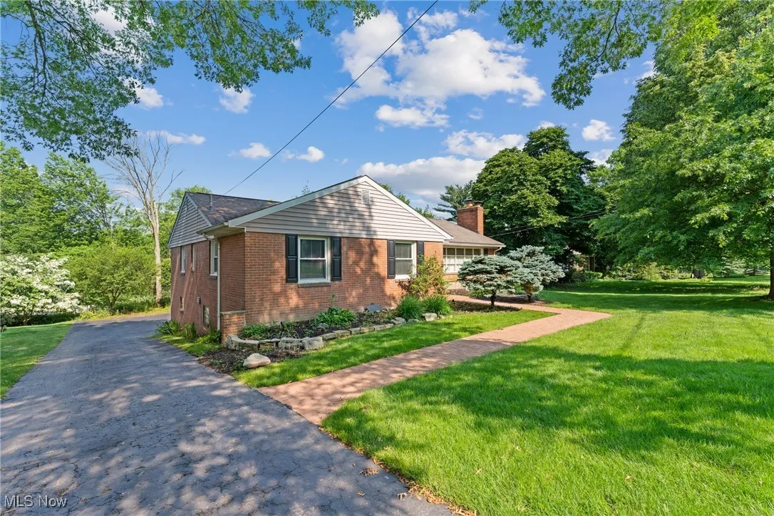 View of home's exterior with brick siding, a lawn, and a chimney