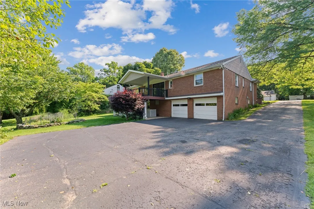 View of front of home featuring brick siding, a garage, and asphalt driveway