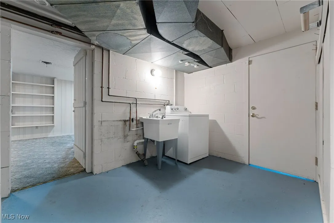 Unfinished basement featuring washer / clothes dryer and concrete block wall