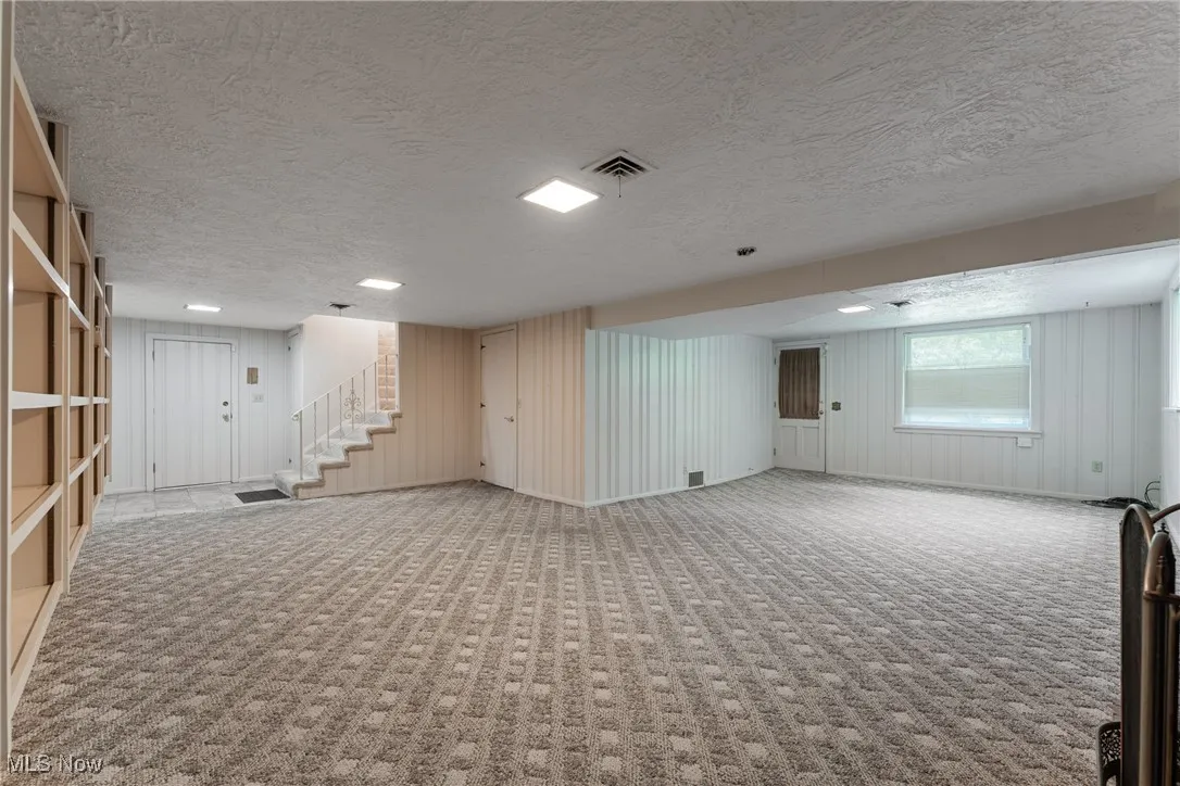 Basement featuring carpet, a textured ceiling, and stairway
