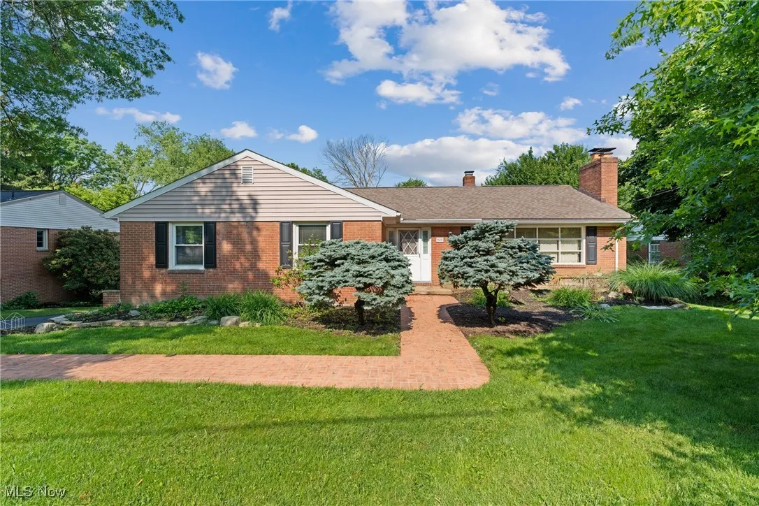 Ranch-style home with brick siding, a front yard, and a chimney