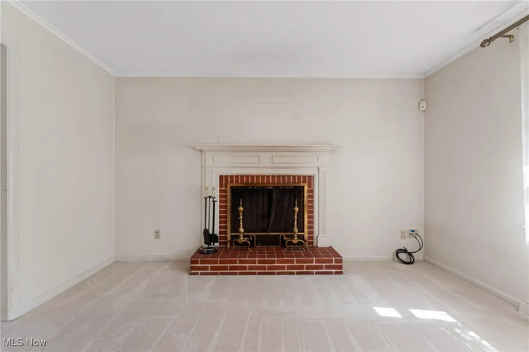 Detailed view of crown molding, carpet floors, and a brick fireplace