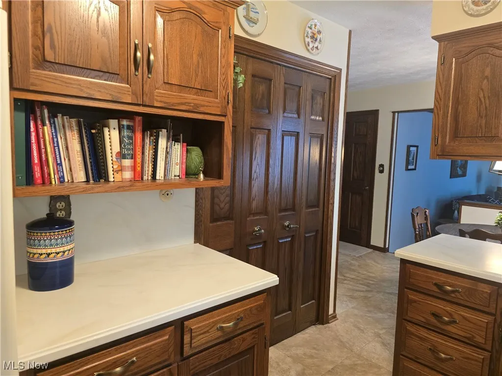 Kitchen with open shelves, light countertops, a textured ceiling, and brown cabinets