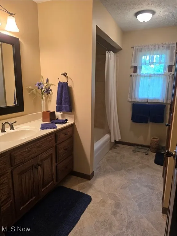 Bathroom with vanity, a textured ceiling, and baseboards