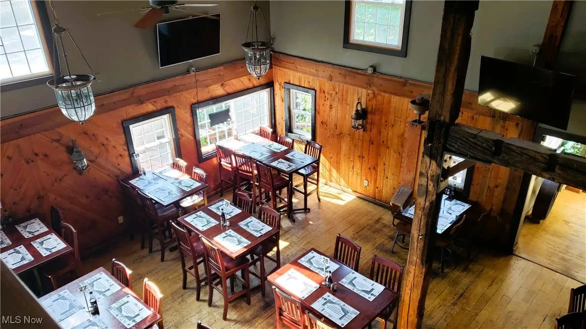 Living room featuring wood walls, hardwood / wood-style floors, and a ceiling fan