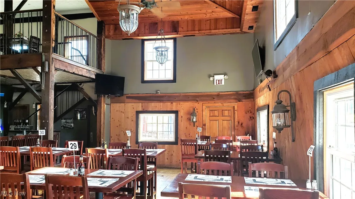 Dining room featuring a towering ceiling, wood walls, wooden ceiling, and wood finished floors