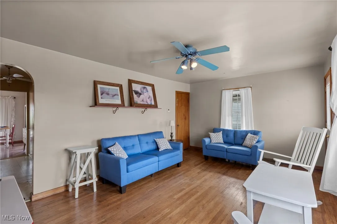 Living room featuring a ceiling fan, wood finished floors, arched walkways, and baseboards