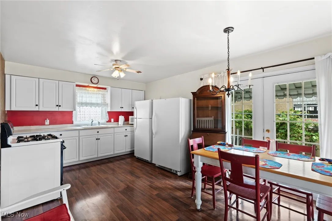 Kitchen featuring freestanding refrigerator, gas range oven, a sink, light countertops, and a chandelier