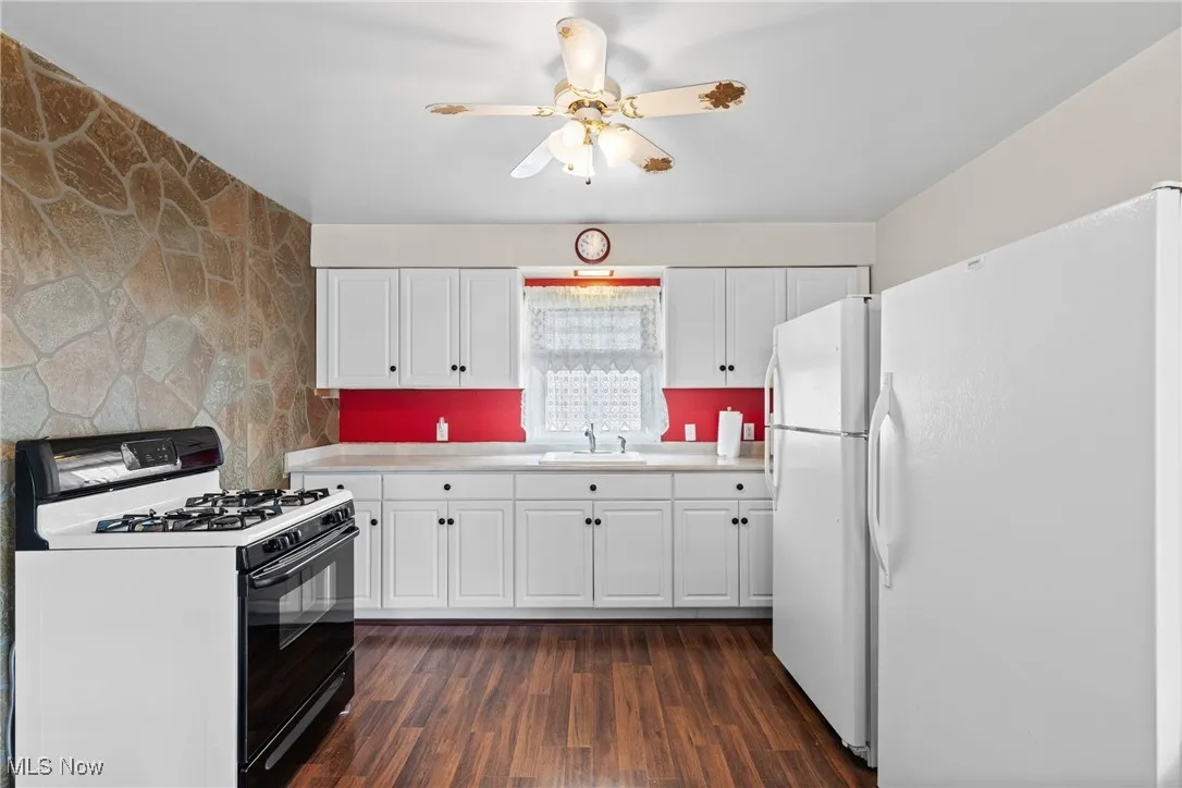 Kitchen featuring freestanding refrigerator, range with gas cooktop, a sink, and light countertops
