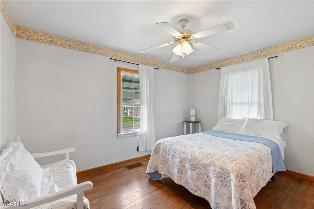 Bedroom with baseboards, wood-type flooring, and a ceiling fan