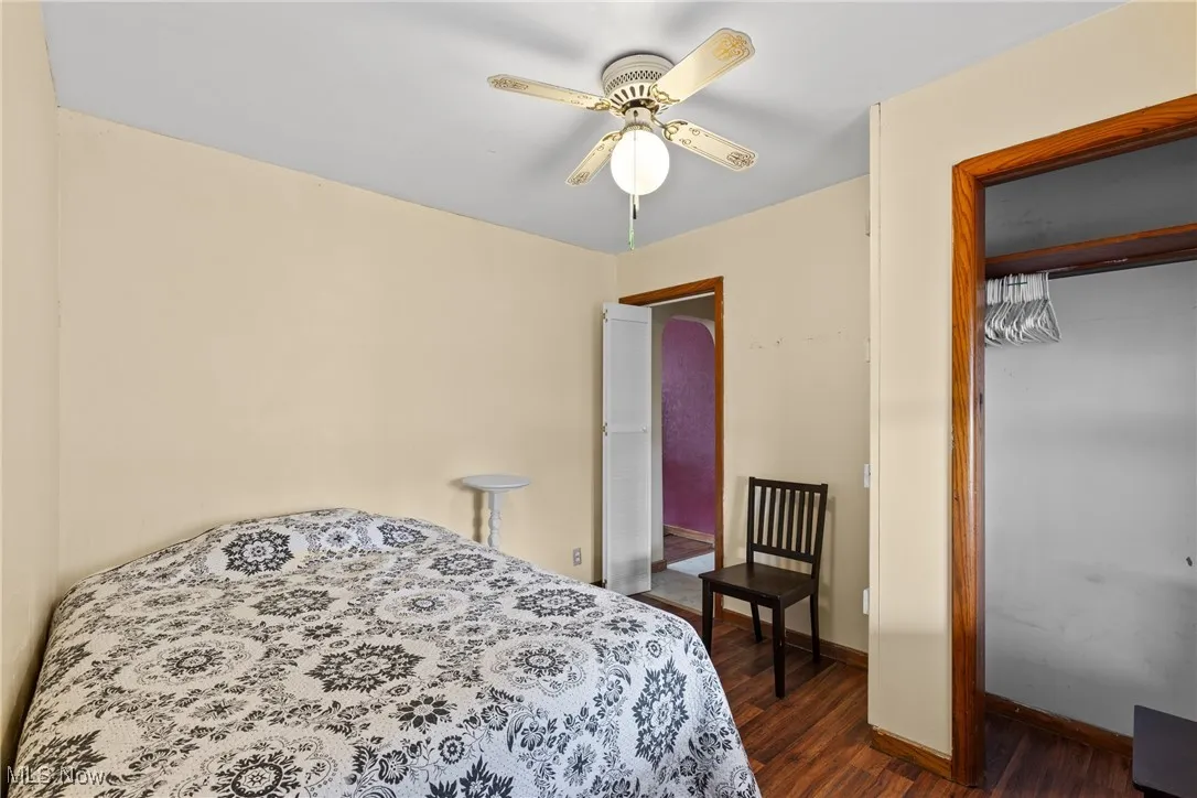 Bedroom with dark wood-style flooring, a closet, baseboards, and ceiling fan