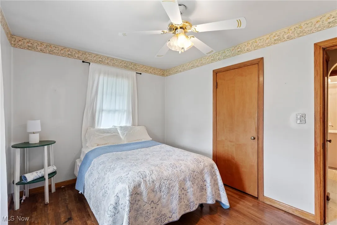 Bedroom featuring wood finished floors, baseboards, a ceiling fan, and a closet