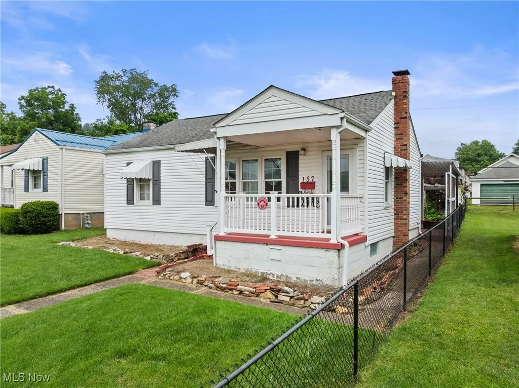 View of front of property with covered porch, a chimney, and a shingled roof