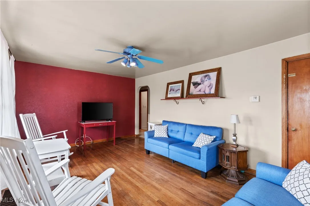 Living room featuring arched walkways, wood finished floors, and a ceiling fan