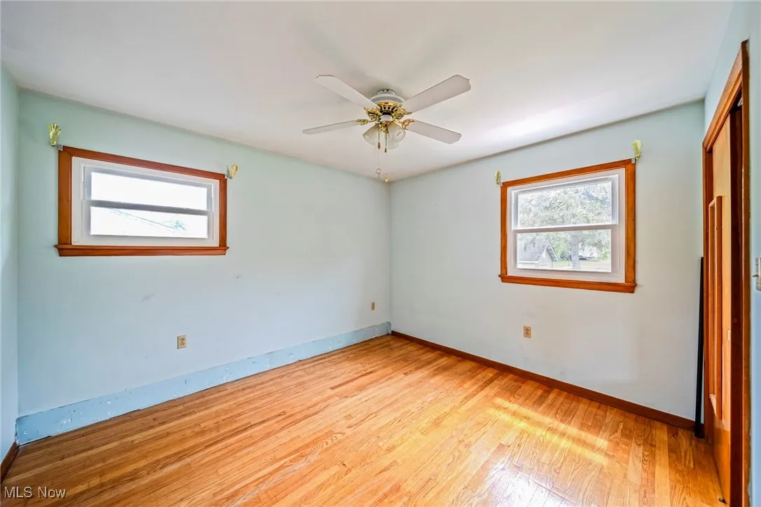 Unfurnished bedroom with light wood-style floors, multiple windows, baseboards, and a ceiling fan