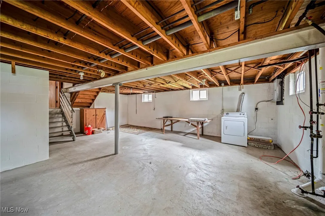 Below grade area featuring washer / clothes dryer, stairway, concrete block wall, and electric panel