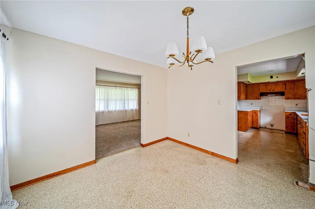 Unfurnished dining area with a chandelier and baseboards