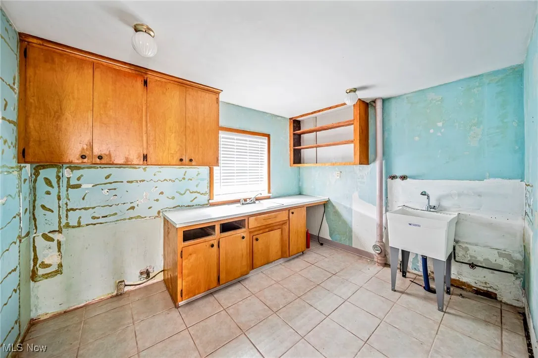 Kitchen featuring a sink, open shelves, light countertops, and light tile patterned floors