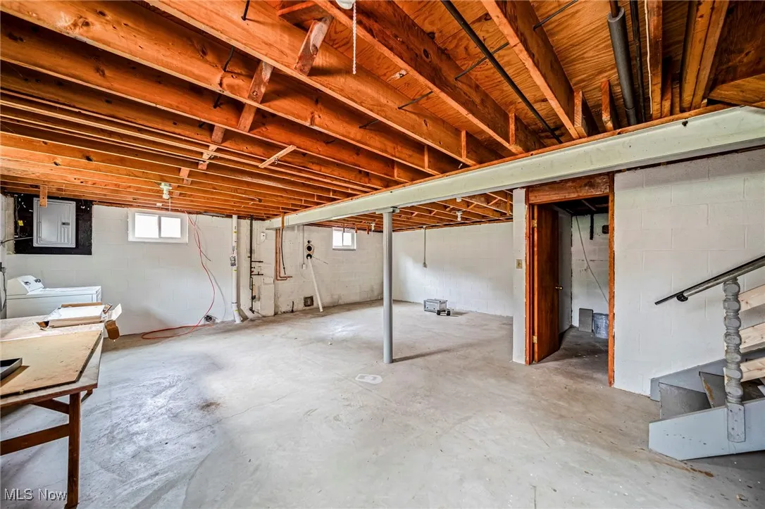 Below grade area featuring washer and dryer, electric panel, and stairway