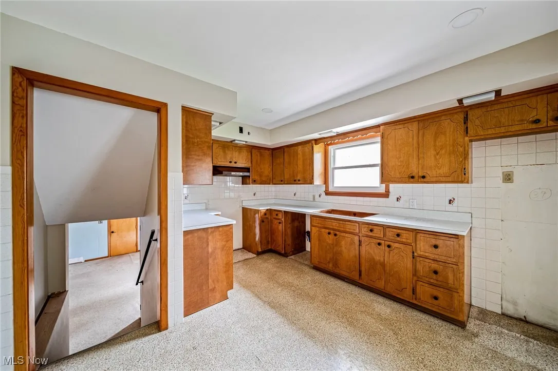 Kitchen with brown cabinets, under cabinet range hood, and light countertops